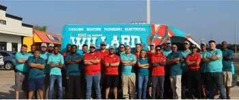 A large group of Willard employees pose in front of a company van.