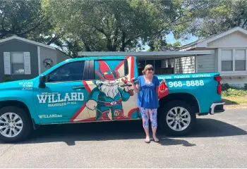 A smiling woman stands by a Willard service truck.