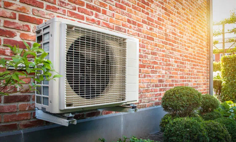 Side view of outdoor energy unit hanging on brick wall of house on a sunny day