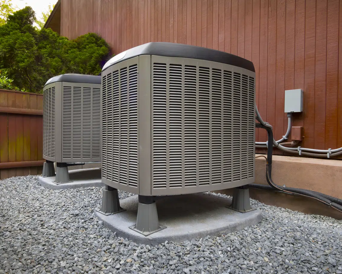 Two HVAC units outside a brown home.