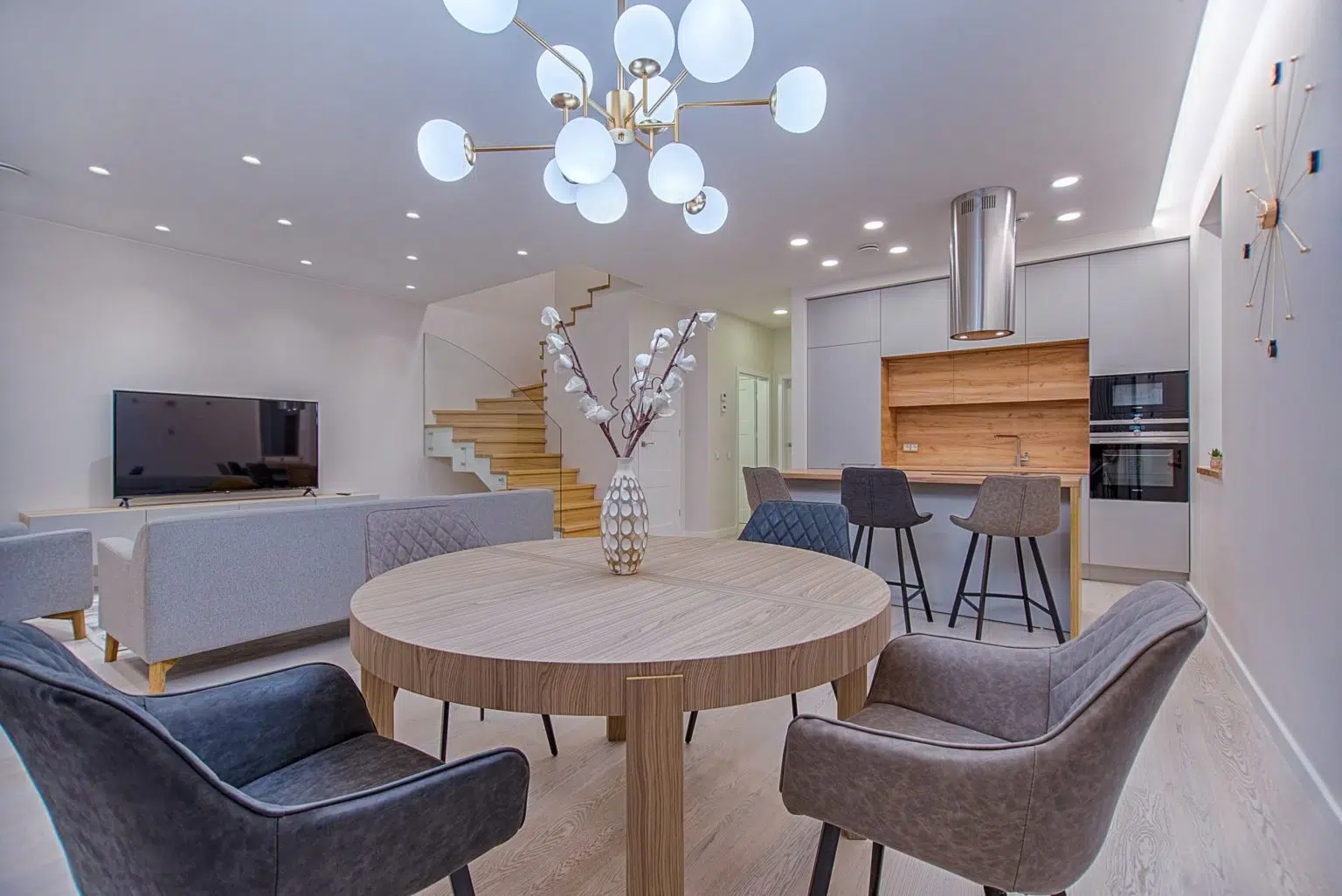 Modern dining room and living area with recessed lighting and decorative lighting fixture over dining table.