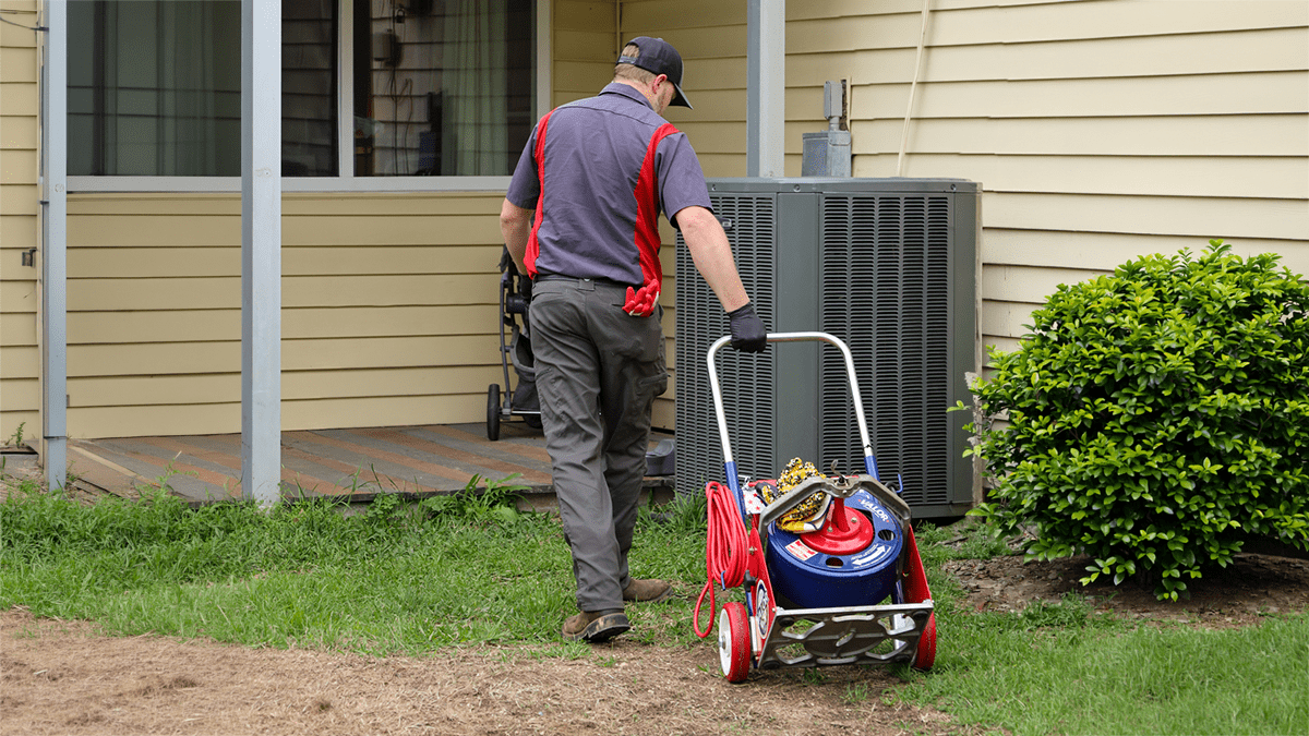 Technician bringing drain cleaning equipment to a home for professional drain service