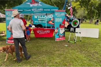 A Willard event booth with a throwing game on a grassy area.