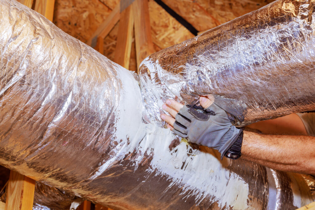 Technicians hand sealing a home's ductwork