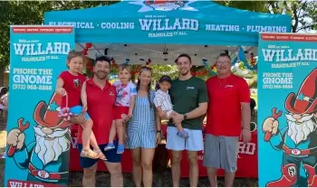 A group poses under a Willard event tent with gnome banners.