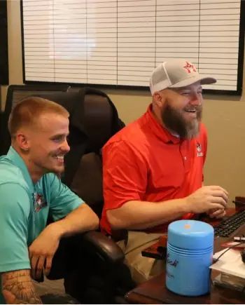 Two smiling Willard employees work at a computer.